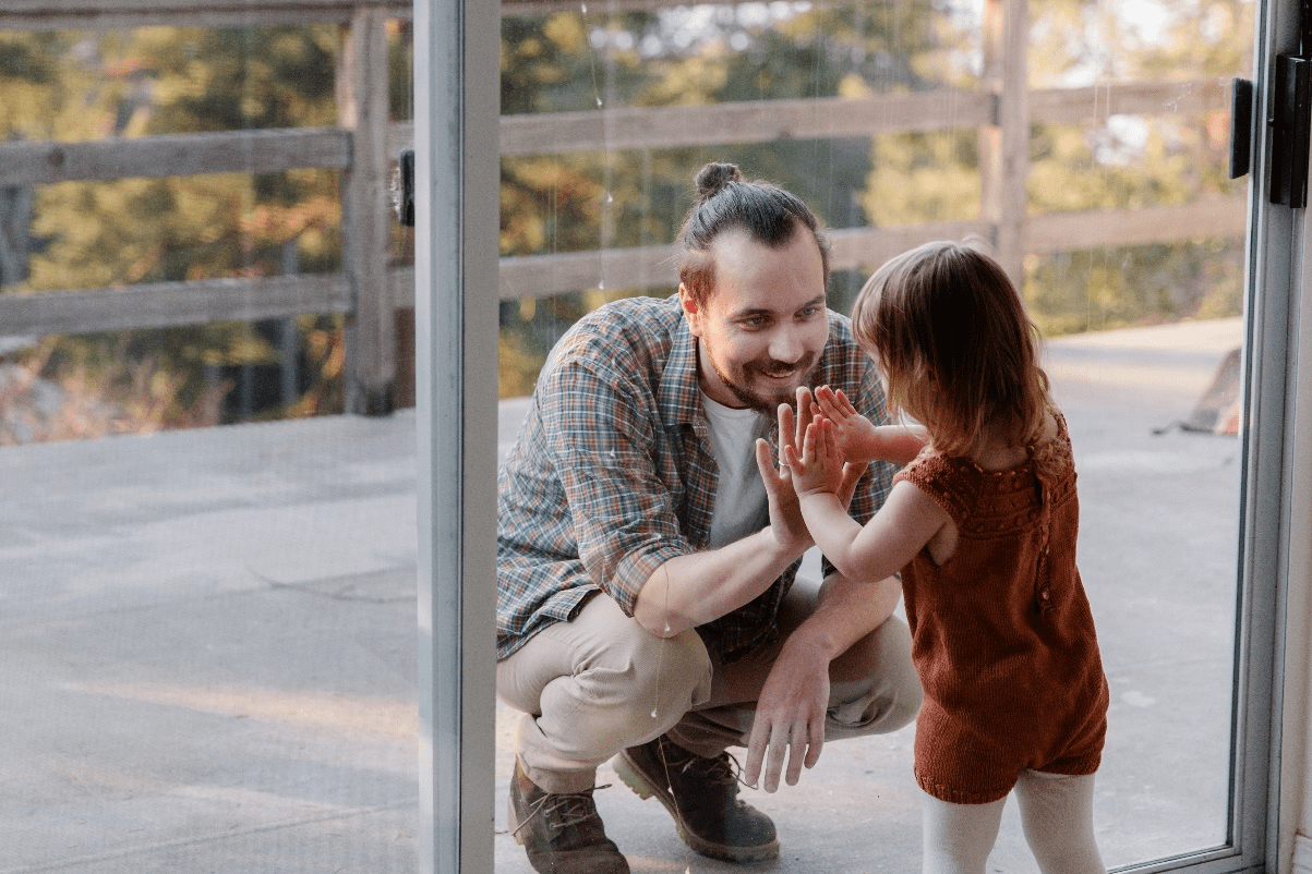 A father and child standing on opposite sides of a glass door